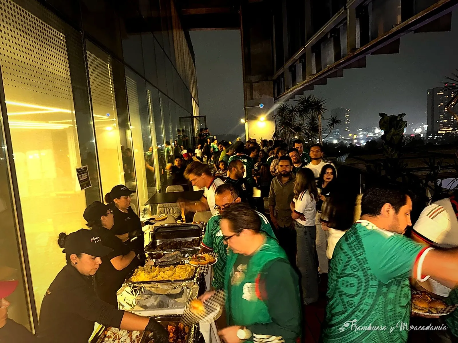 Invitados sirviéndose del buffet americano en evento nocturno en terraza