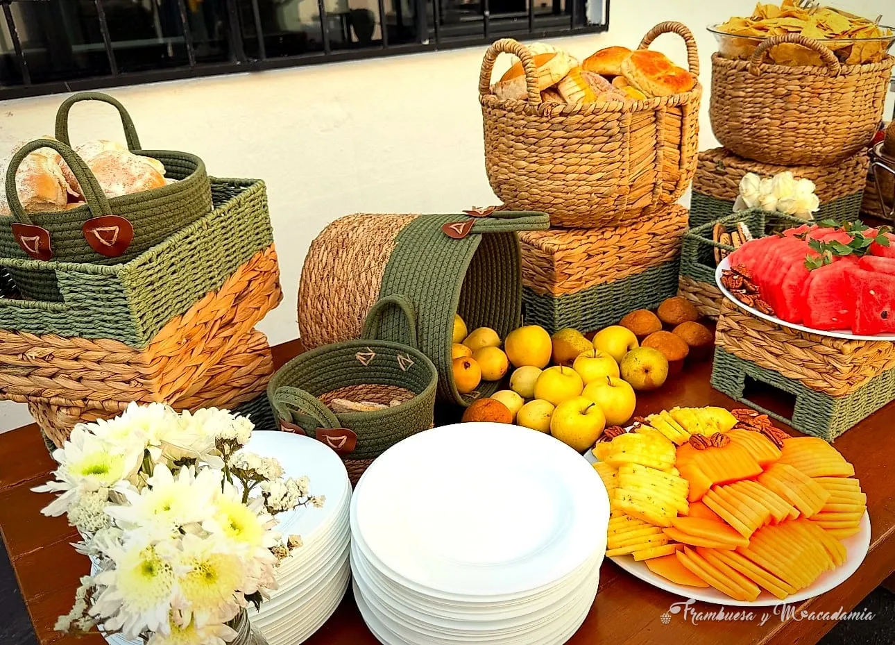 Mesa de brunch con canastas de pan artesanal, fruta de temporada y flores blancas