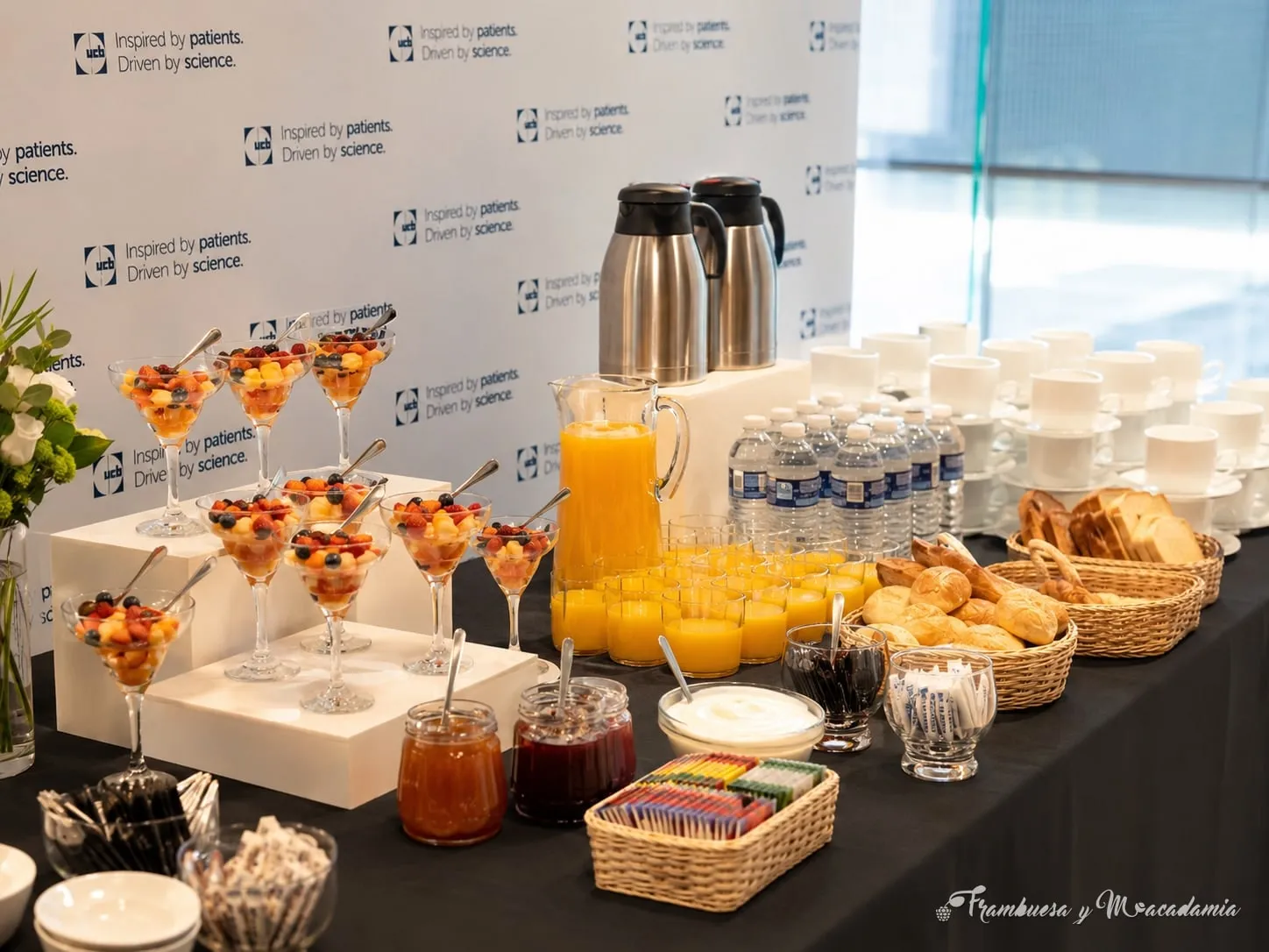 Montaje de coffee break corporativo con café, jugo, fruta y panes en evento de empresa