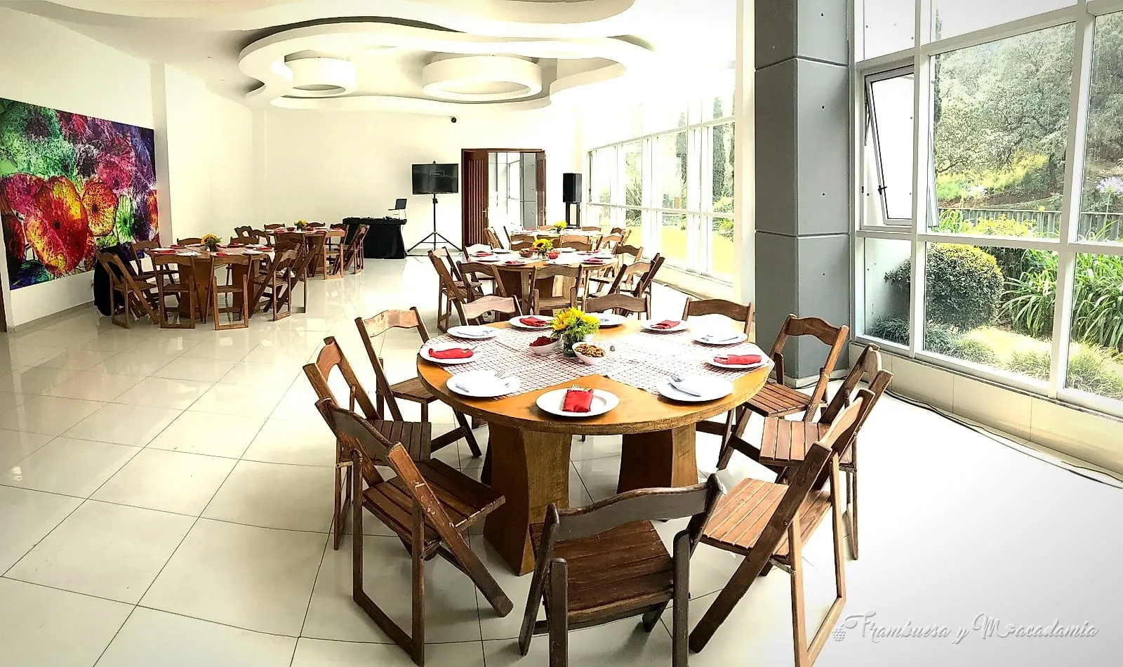 Salón montado completo con mesas redondas y sillas de madera