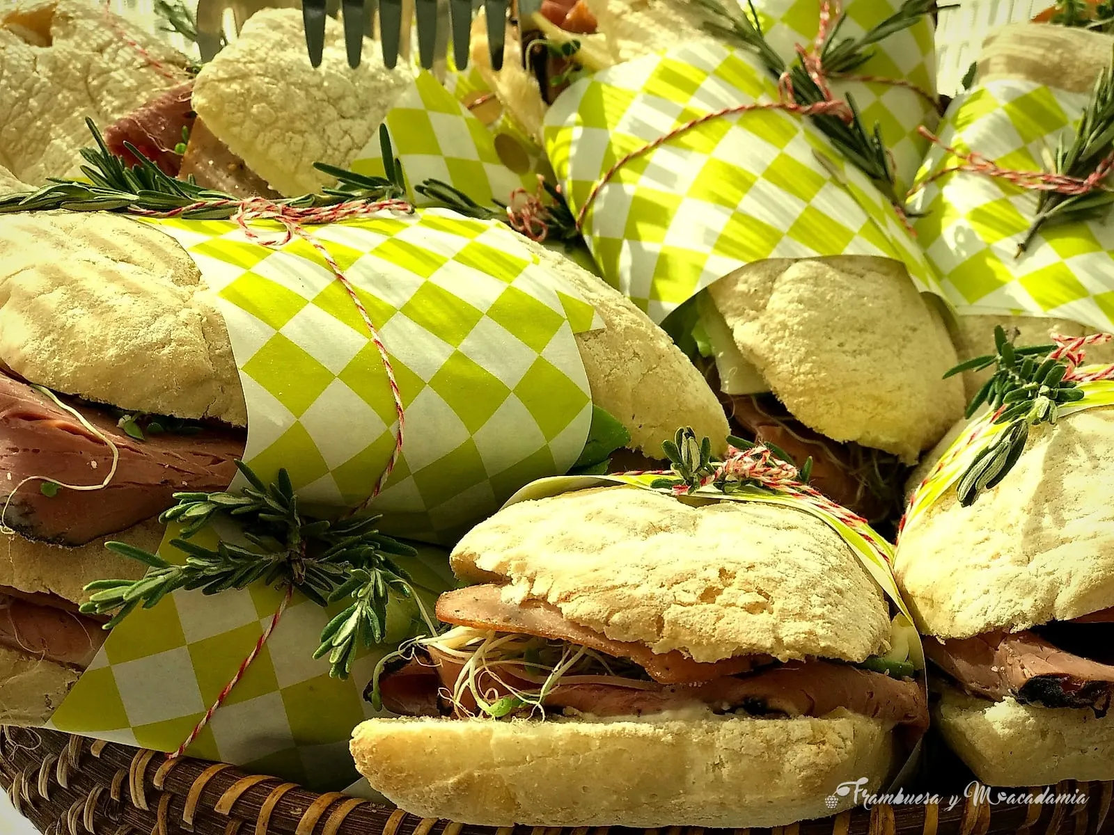 Tortas y panninis envueltos en papel con romero fresco en canasta