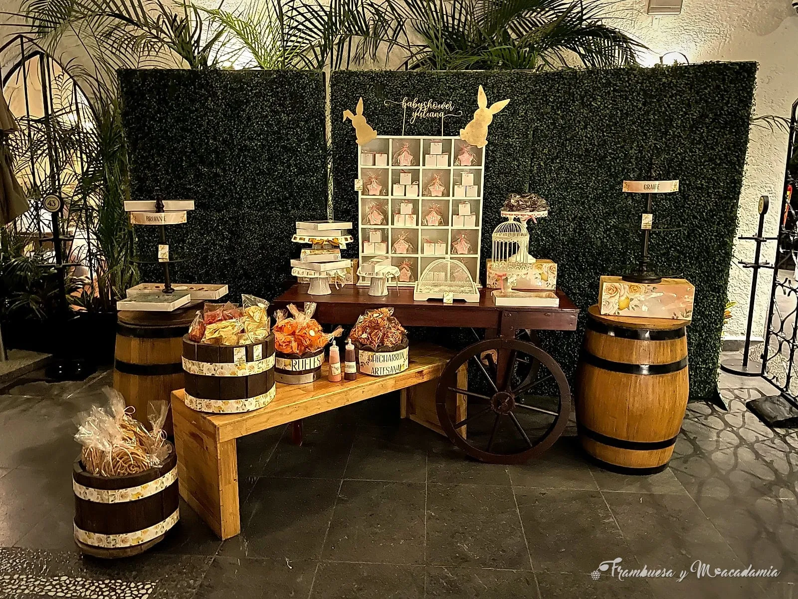 Carreta y barricas con dulces y botanas artesanales en baby shower con muro verde