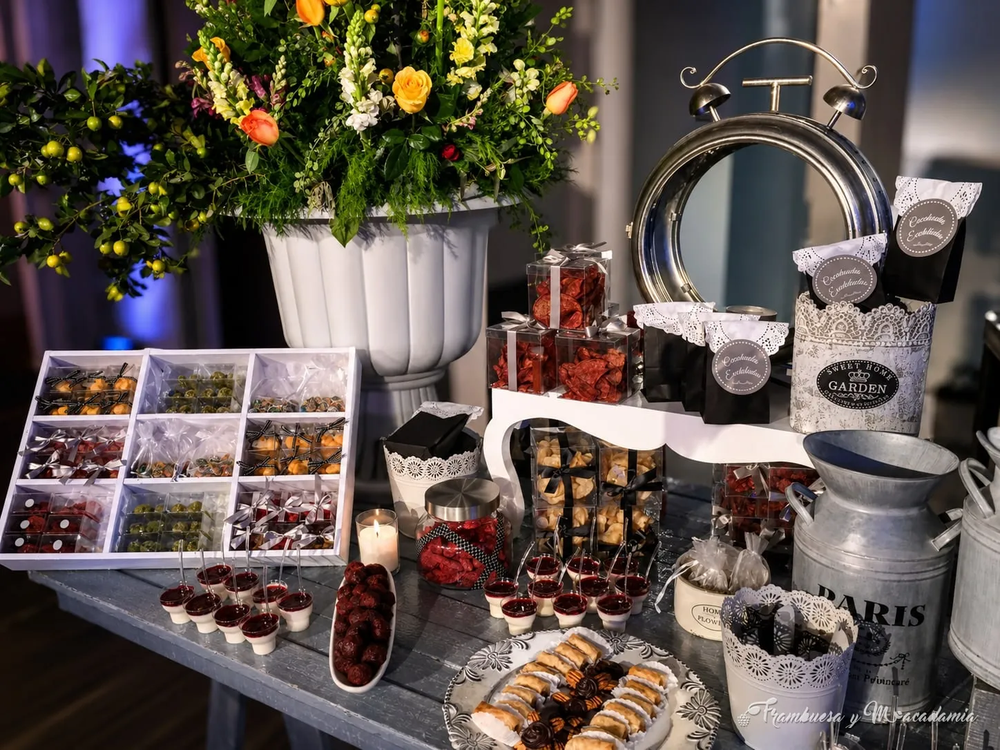 Mesa de dulces con cajas de madera, flores y latas parisinas