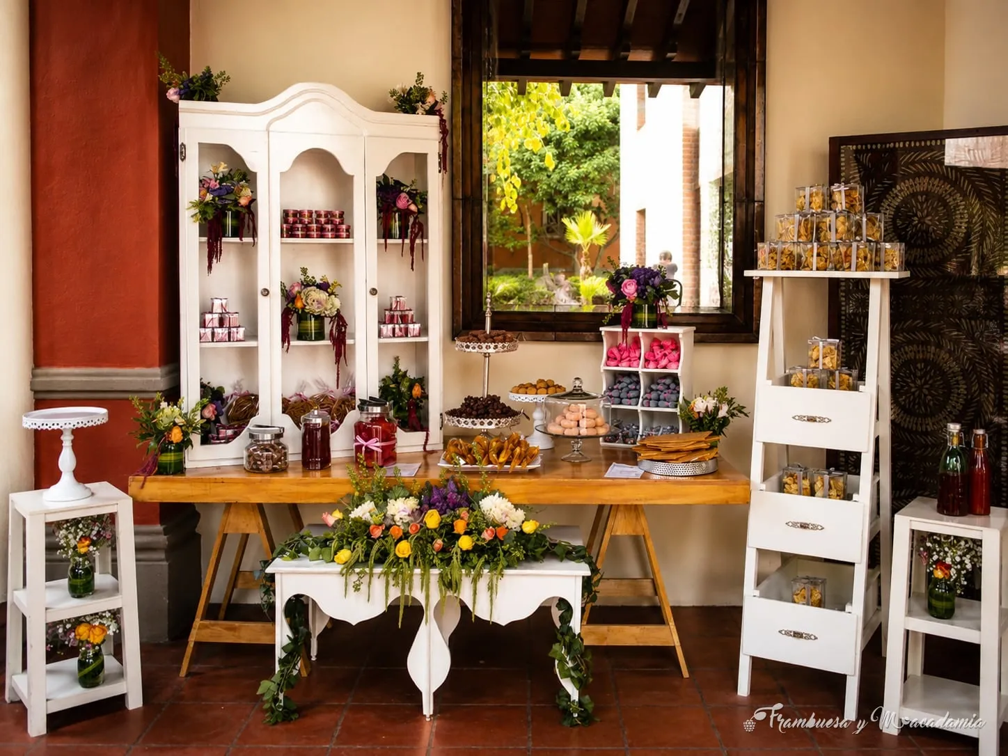 Vitrina blanca de postres con flores en salón de fiestas
