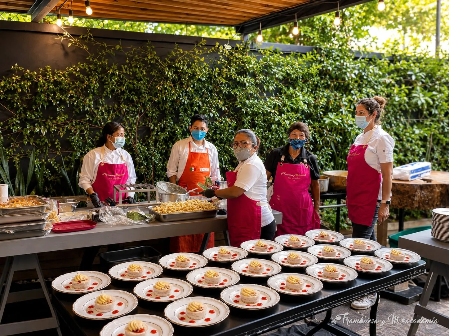 Equipo de Frambuesa y Macadamia emplatando el banquete en cocina montada en jardín